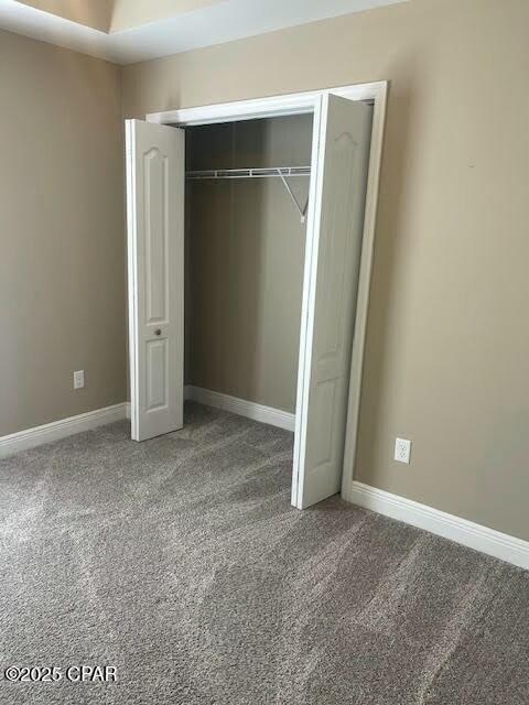 unfurnished bedroom featuring carpet, baseboards, and a closet