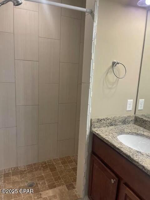 full bathroom with a tile shower and vanity