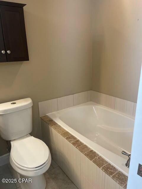 bathroom with toilet, a bath, and tile patterned floors