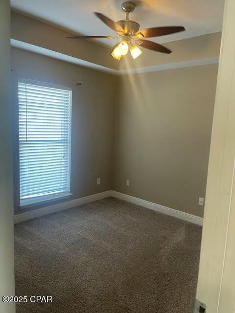 unfurnished room with carpet floors, a ceiling fan, and baseboards