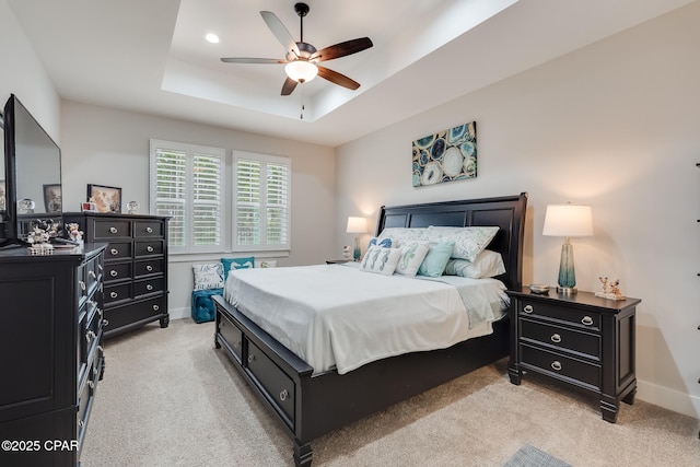 bedroom featuring a ceiling fan, a raised ceiling, light carpet, and baseboards