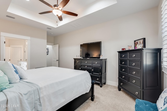 bedroom with light colored carpet, a tray ceiling, visible vents, and baseboards