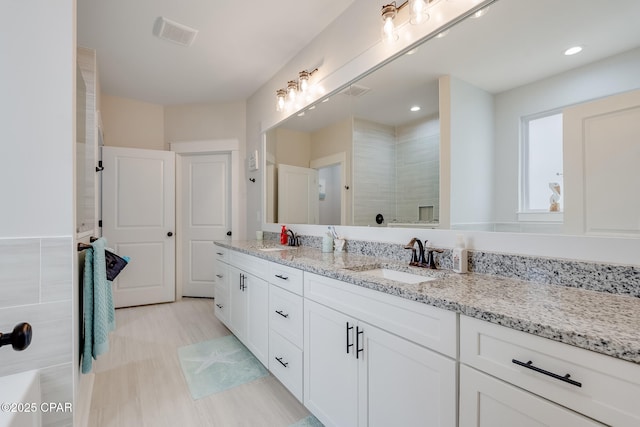 full bathroom featuring vanity, a tile shower, and visible vents