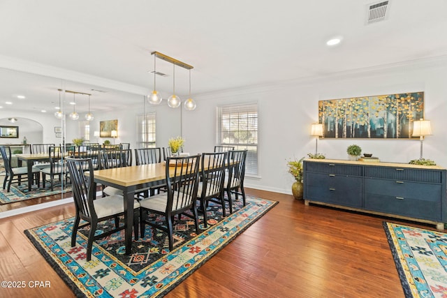 dining space with dark wood-style floors, visible vents, and crown molding