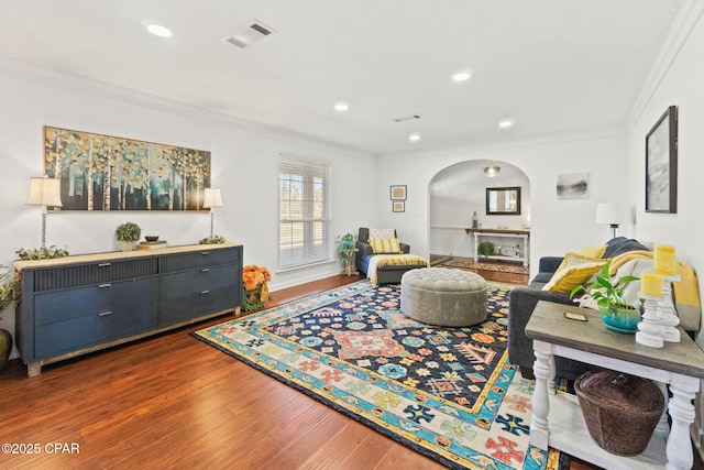 living room with ornamental molding, arched walkways, visible vents, and wood finished floors