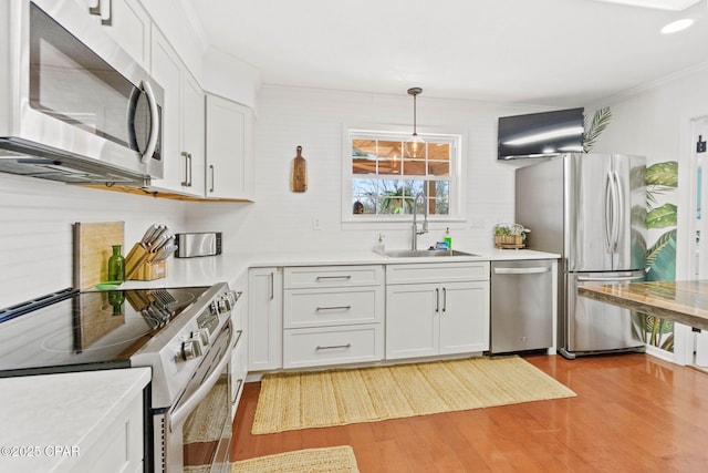 kitchen with stainless steel appliances, a sink, white cabinetry, light wood-style floors, and light countertops