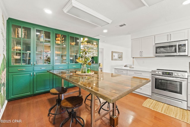 3368 Bevia Rd, Marianna, FL 32446 - kitchen featuring appliances with stainless steel finishes, crown molding, wood finished floors, recessed lighting, and white cabinetry