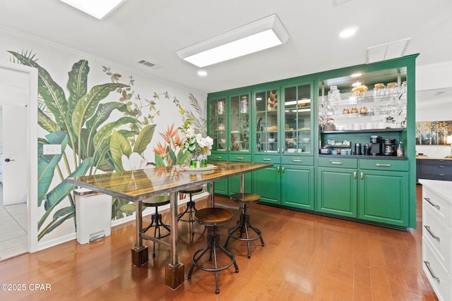 bar with visible vents, wood finished floors, and ornamental molding