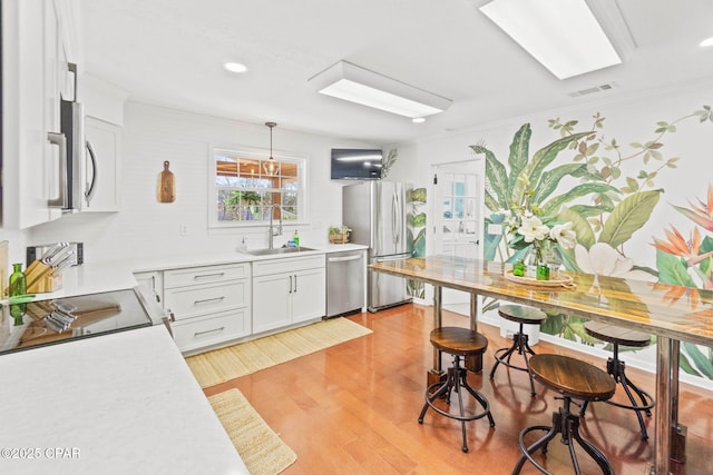 3368 Bevia Rd, Marianna, FL 32446 - kitchen with a sink, stainless steel appliances, light wood finished floors, light countertops, and white cabinetry
