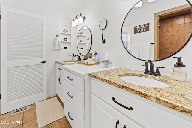 bathroom with visible vents, two vanities, a sink, and ornamental molding