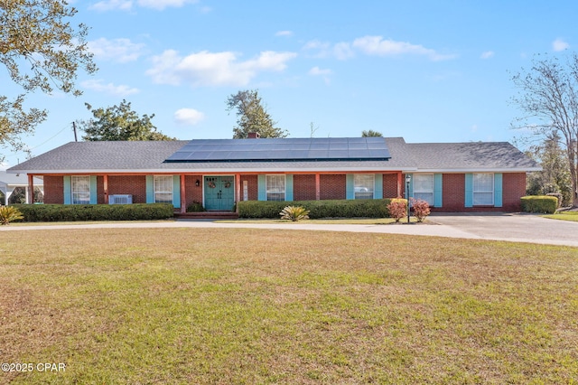 ranch-style house featuring solar panels, brick siding, and a front yard