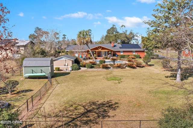 exterior space with a lawn, roof mounted solar panels, a shed, a fenced backyard, and an outdoor structure