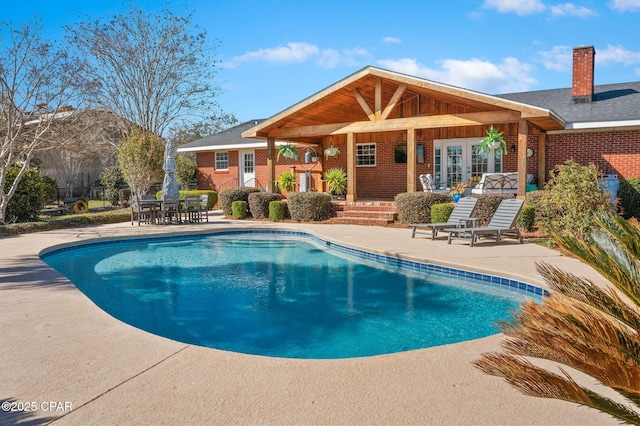 outdoor pool featuring french doors, a patio area, and a mountain view