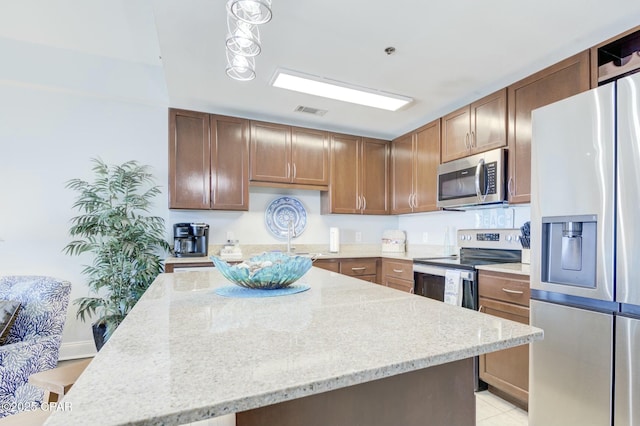 kitchen featuring visible vents, light tile patterned flooring, a center island, light stone counters, and appliances with stainless steel finishes