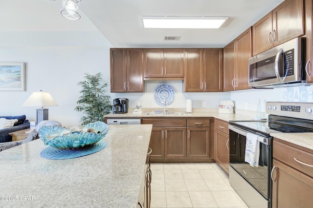 kitchen featuring light stone countertops, appliances with stainless steel finishes, a sink, light tile patterned floors, and visible vents