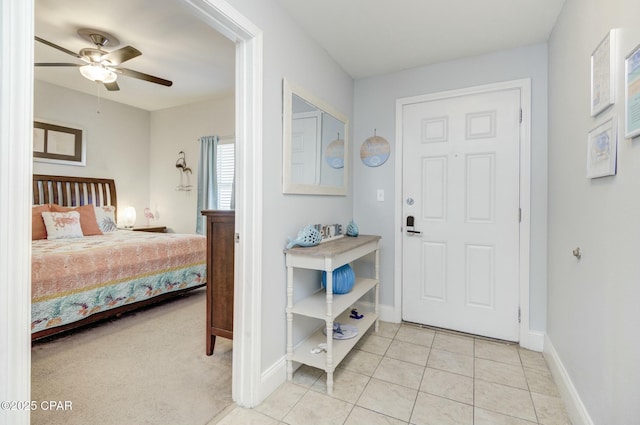 interior space with baseboards, a ceiling fan, and light tile patterned floors