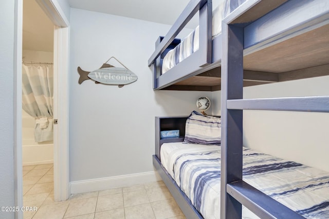 bedroom with tile patterned floors, baseboards, and ensuite bathroom