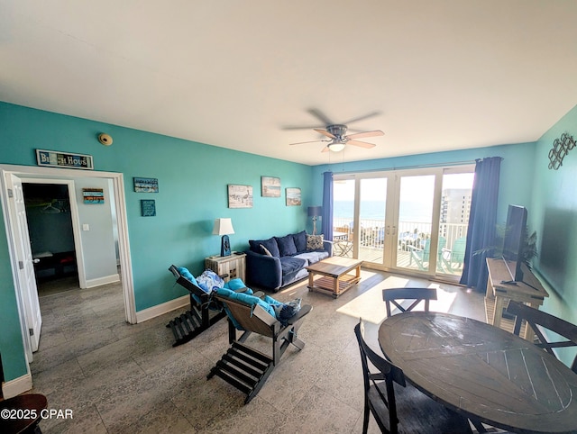 living area with a ceiling fan, french doors, and baseboards