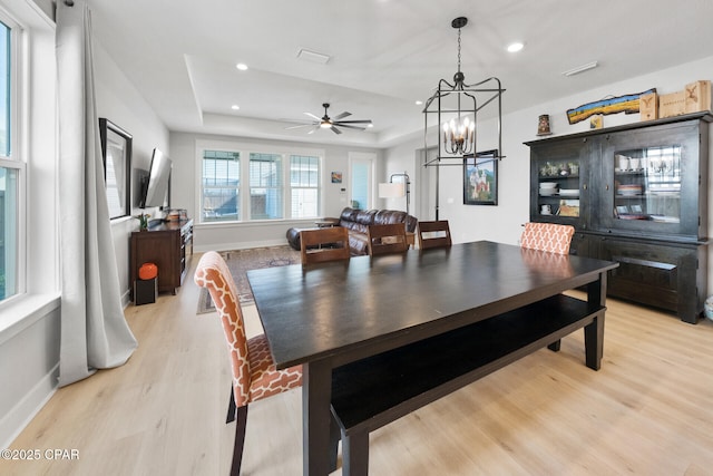 dining space with light wood finished floors, baseboards, a tray ceiling, and recessed lighting