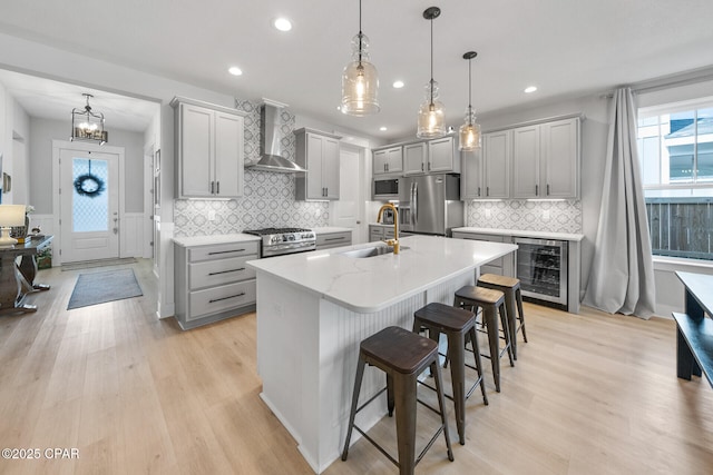 kitchen with gray cabinetry, wall chimney exhaust hood, wine cooler, and stainless steel appliances