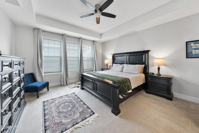 bedroom featuring light colored carpet, a raised ceiling, visible vents, and baseboards