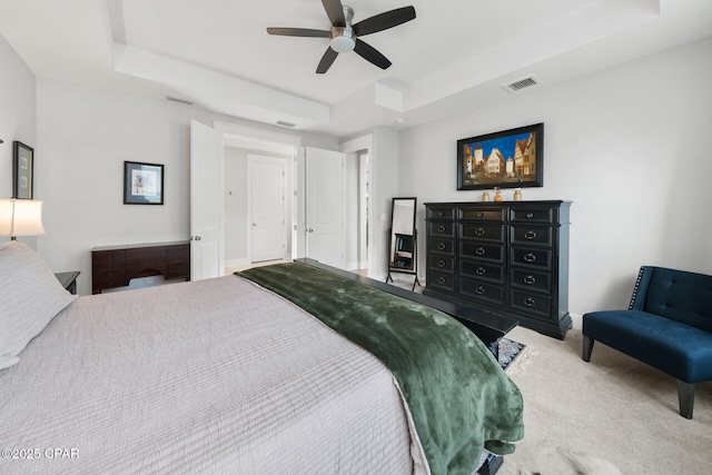 carpeted bedroom featuring a raised ceiling, visible vents, and a ceiling fan