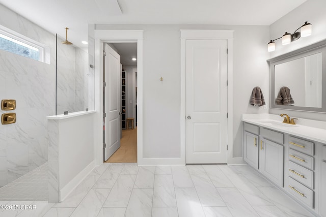 bathroom featuring marble finish floor, a marble finish shower, baseboards, and vanity