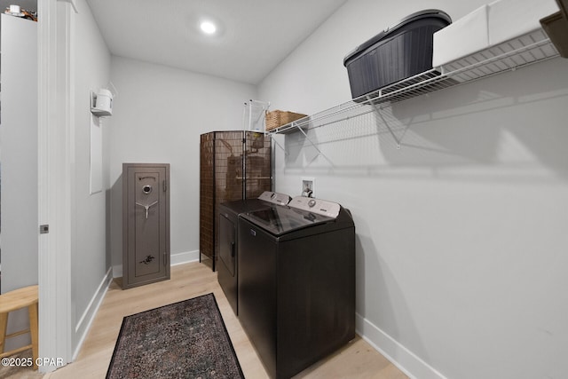 laundry room with laundry area, light wood-type flooring, washing machine and dryer, and baseboards