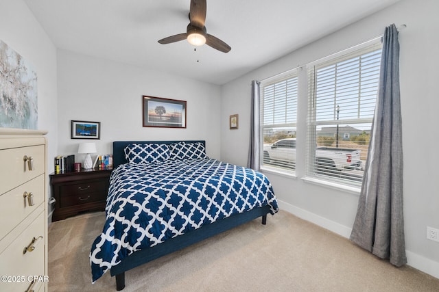 bedroom featuring light carpet, a ceiling fan, and baseboards