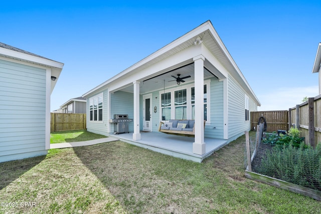 back of house with a ceiling fan, a fenced backyard, a lawn, and a patio