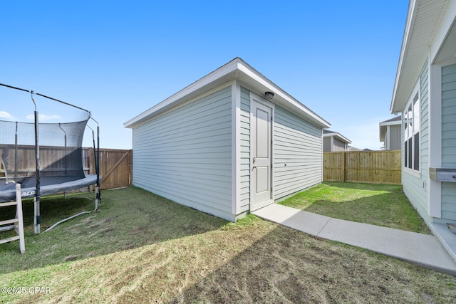 view of outbuilding with a fenced backyard, a trampoline, and an outdoor structure