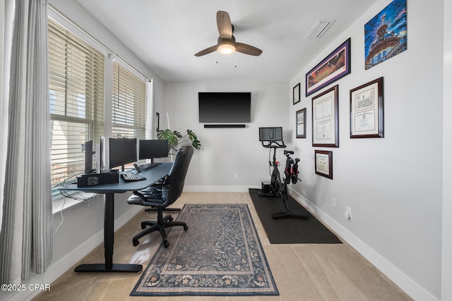 carpeted office with baseboards, visible vents, and a ceiling fan