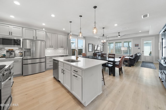 kitchen featuring light wood finished floors, light countertops, visible vents, appliances with stainless steel finishes, and a sink