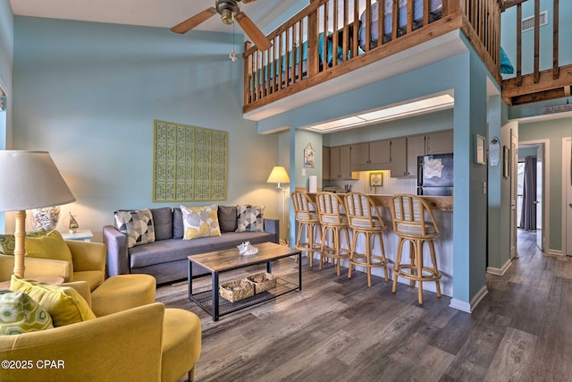 living room featuring visible vents, baseboards, a ceiling fan, a towering ceiling, and dark wood-style flooring