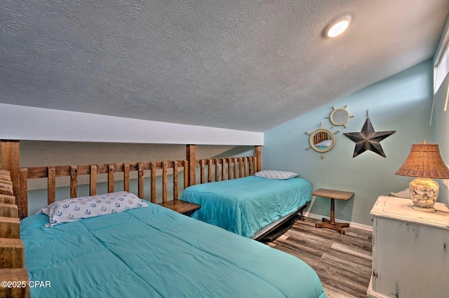 bedroom featuring vaulted ceiling, a textured ceiling, baseboards, and wood finished floors