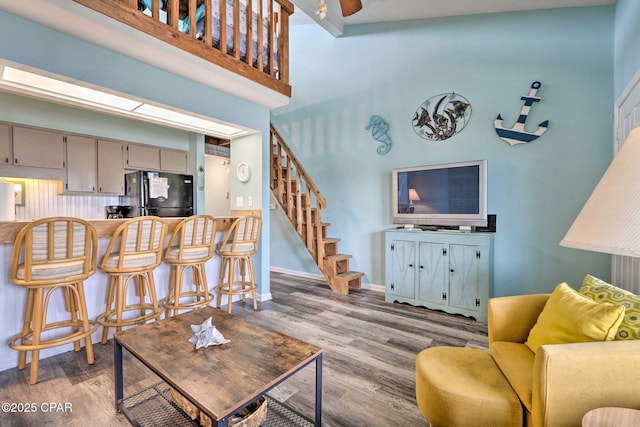 living room with baseboards, a high ceiling, stairway, and wood finished floors