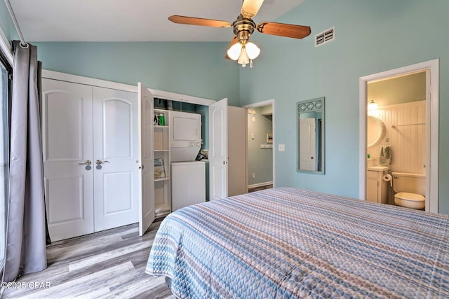 bedroom with wood finished floors, visible vents, vaulted ceiling, a closet, and ensuite bath