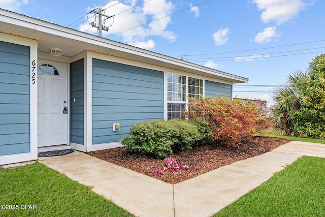 view of exterior entry featuring a lawn