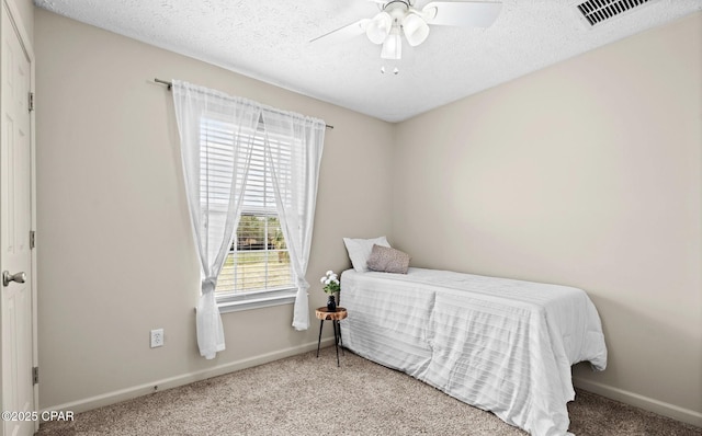 bedroom featuring carpet, visible vents, a textured ceiling, and baseboards