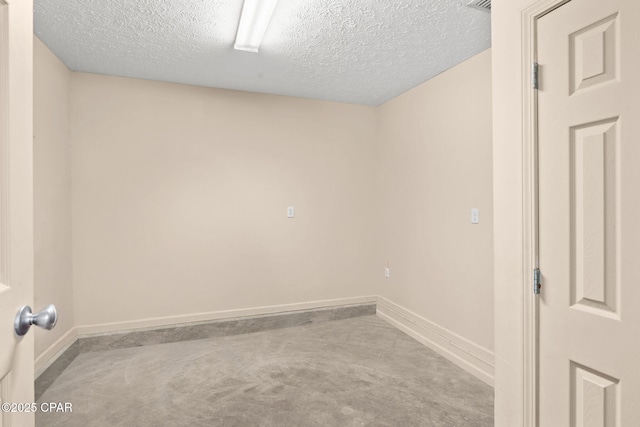 spare room featuring concrete floors, a textured ceiling, and baseboards