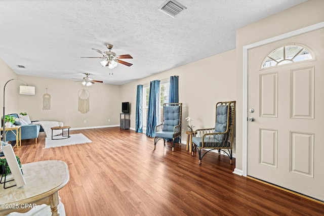 foyer entrance featuring baseboards, a textured ceiling, visible vents, and wood finished floors