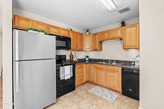 kitchen with a textured ceiling, black appliances, a sink, and visible vents