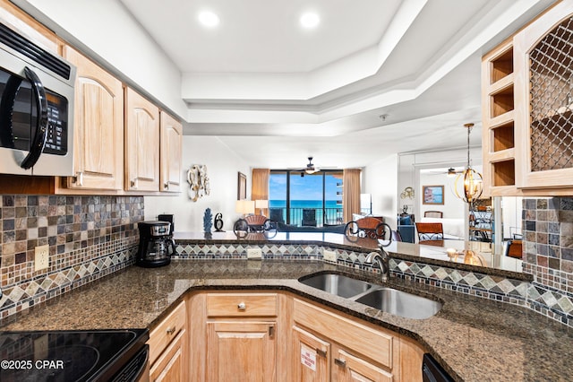 kitchen featuring a sink, stainless steel microwave, dark stone counters, and light brown cabinets