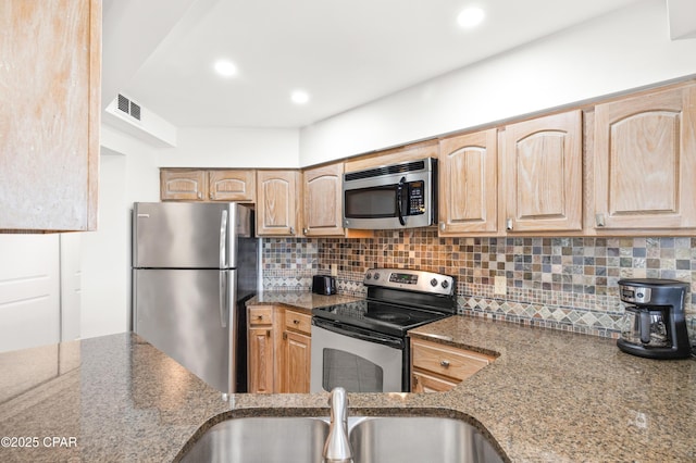 kitchen with a sink, visible vents, appliances with stainless steel finishes, backsplash, and light brown cabinetry