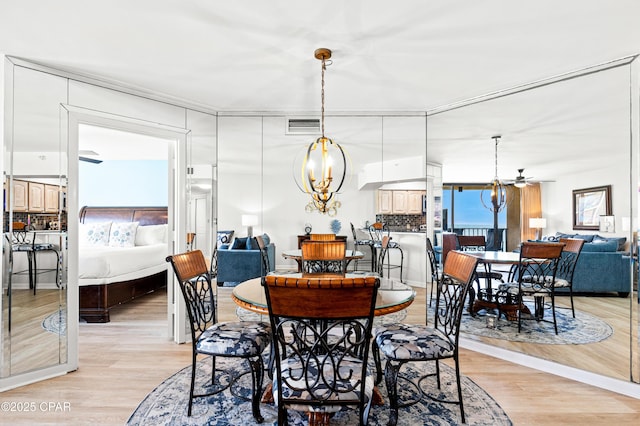 dining space featuring light wood-style floors, visible vents, and ceiling fan with notable chandelier