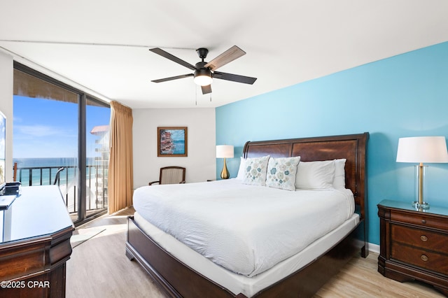 bedroom with baseboards, a ceiling fan, wood finished floors, access to outside, and expansive windows