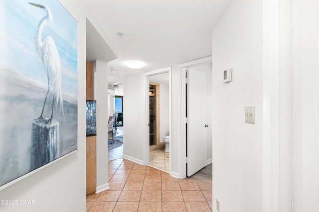 hallway featuring light tile patterned floors and baseboards