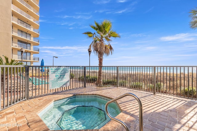 view of pool with a water view, a beach view, and a community hot tub