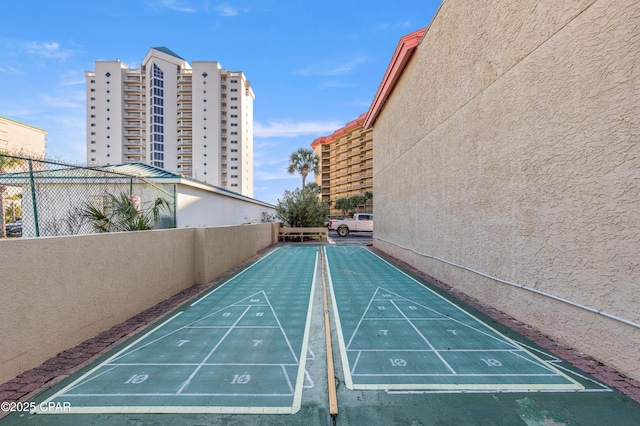 surrounding community with fence and shuffleboard