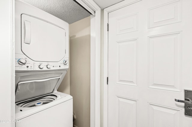 washroom featuring stacked washer and clothes dryer, a textured ceiling, and laundry area